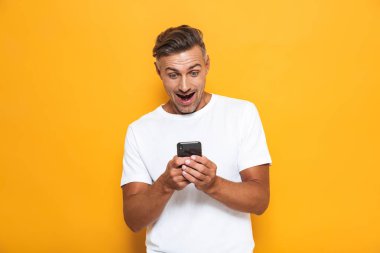 Mutlu adam cep telefonuyla sarı duvar arka plan üzerinde izole poz.