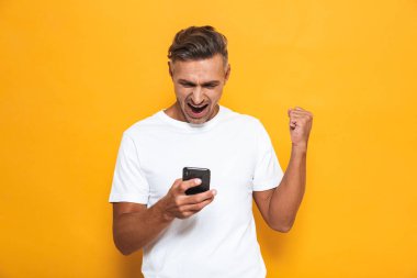 Mutlu adam cep telefonuyla sarı duvar arka plan üzerinde izole poz.