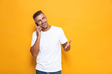 Duygusal adam cep telefonuyla konuşurken sarı duvar arka plan üzerinde izole poz.