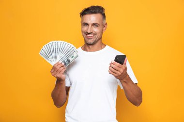 Neşeli adam 30'lu yaşlarda beyaz t-shirt holding cep telefonu görüntüsünü ve 