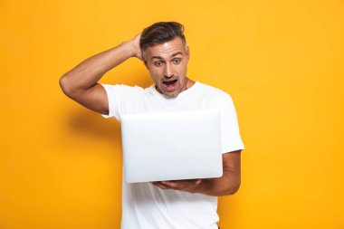 Neşeli adam 30'lu yaşlarda beyaz t-shirt tutarak ve silve kullanarak görüntü