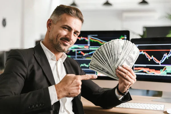 仕事をしながらお金のファンを保持する魅力的なビジネスマンをイメージ — ストック写真