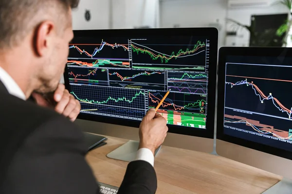 Foto eines erfolgreichen Geschäftsmannes, der im Büro am Tisch sitzt und — Stockfoto