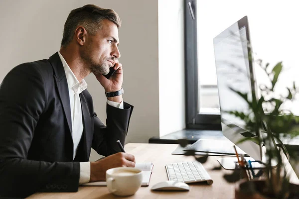 Образ успішного бізнесмена, який розмовляє на мобільному телефоні під час роботи — стокове фото