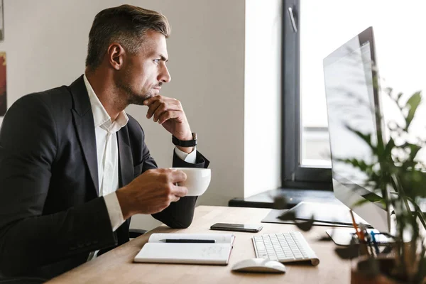 Imagen del empresario europeo tomando café mientras trabaja en c — Foto de Stock