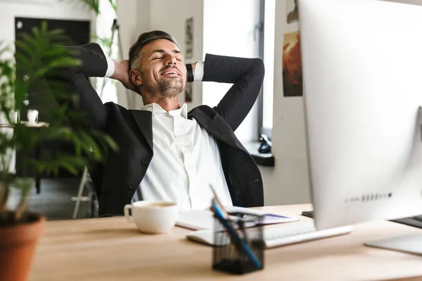 Photo d'un homme d'affaires prospère souriant assis à son bureau — Photo