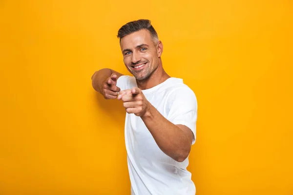 Feliz animado homem posando isolado sobre amarelo parede fundo apontando . — Fotografia de Stock