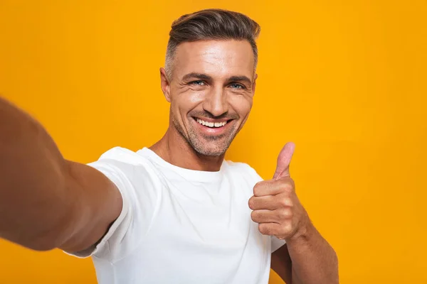 Imagem de homem atraente 30 anos em branco t-shirt sorrindo e tomando — Fotografia de Stock