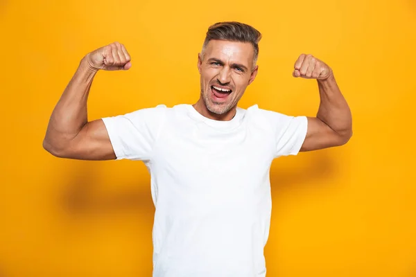 Bild eines starken Mannes um die 30 in weißem T-Shirt, der die Arme hebt und zeigt — Stockfoto