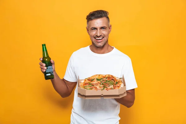 Imagen del hombre sonriente de 30 años en camiseta blanca bebiendo cerveza y eati — Foto de Stock