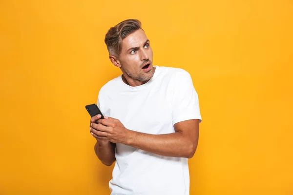 Imagen del hombre irritado de 30 años en camiseta blanca sosteniendo y hablando — Foto de Stock