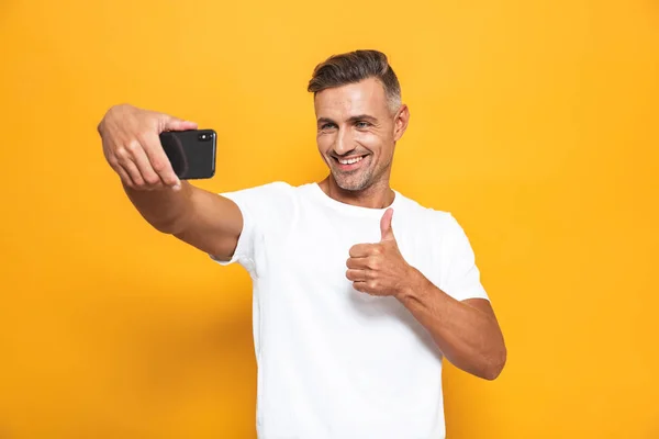 Imagen de hombre atractivo 30s en camiseta blanca sonriendo y tomando — Foto de Stock