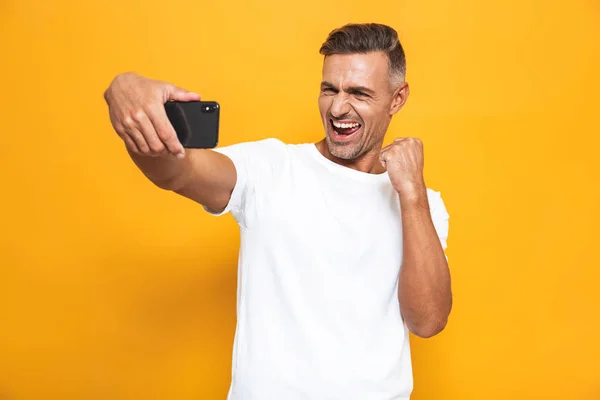 Imagen del hombre sin afeitar de 30 años en camiseta blanca sonriendo y tomando se — Foto de Stock