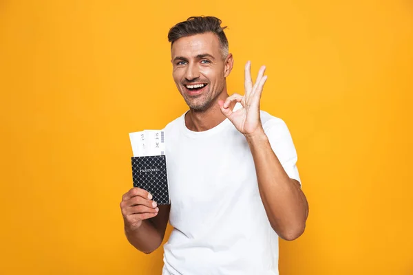 Imagem de homem alegre 30 anos em branco t-shirt segurando passaporte e tr — Fotografia de Stock