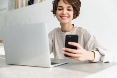 dizüstü bilgisayar üzerinde çalışan genç kadın gülümsüyor