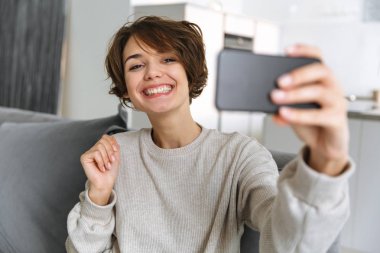 Evde bir kanepede oturan mutlu genç kadın