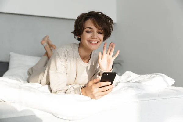 Lächelndes junges Mädchen entspannt sich im Bett — Stockfoto