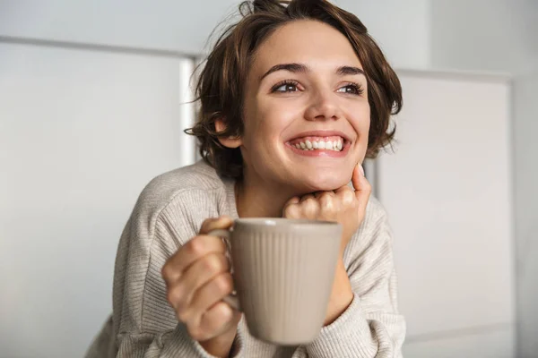 Sorridente giovane donna che beve una tazza di tè — Foto Stock
