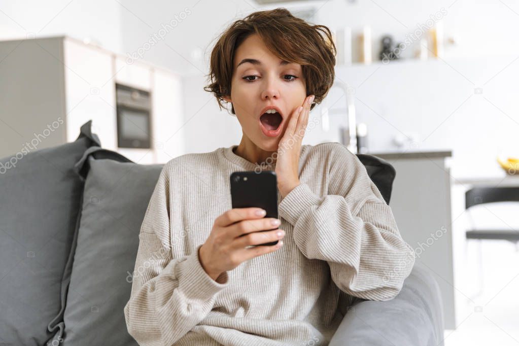 Happy young woman sitting on a couch at home