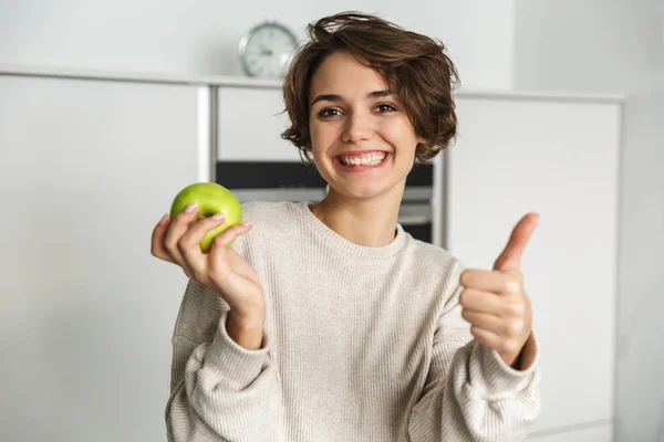 Uśmiechnięta młoda kobieta trzymająca zielone jabłko — Zdjęcie stockowe