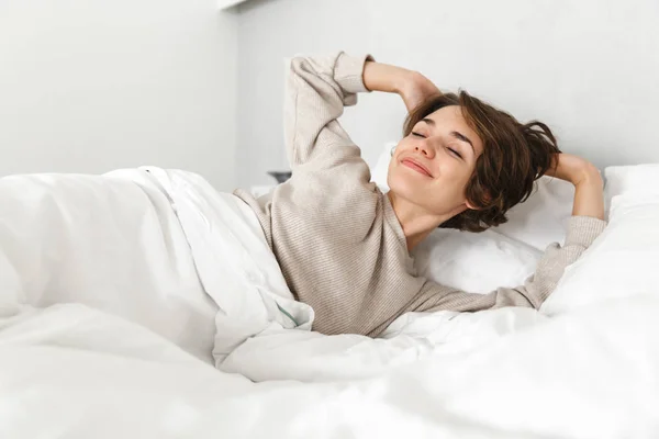 Glimlachend jong meisje ontspannen in bed in de ochtend — Stockfoto