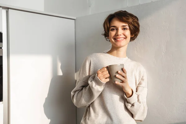 Jovencita sonriente tomando una taza de té — Foto de Stock
