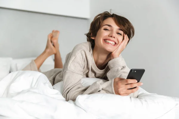 Sonriente chica joven relajarse en la cama — Foto de Stock