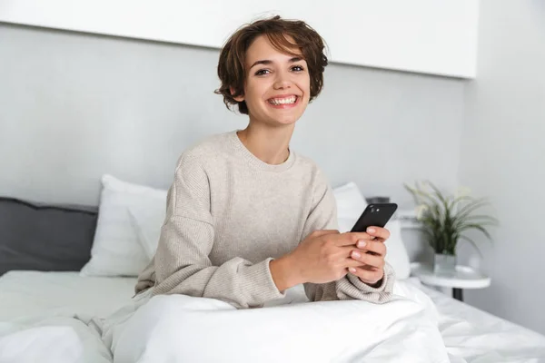 Lächelndes junges Mädchen entspannt sich im Bett — Stockfoto