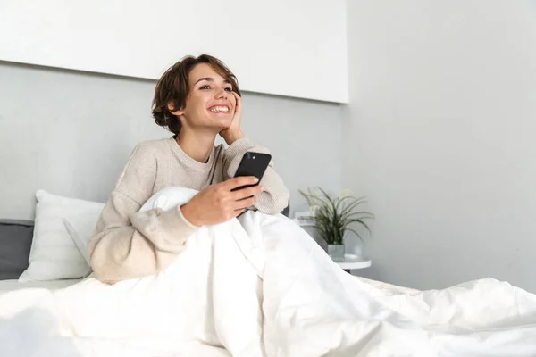 Lächelndes junges Mädchen entspannt sich im Bett — Stockfoto
