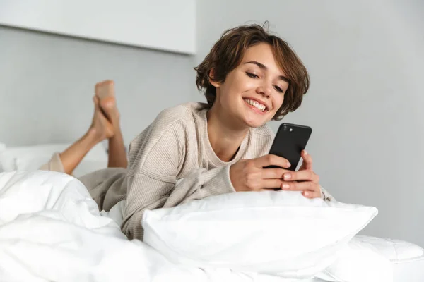 Lächelndes junges Mädchen entspannt sich im Bett — Stockfoto