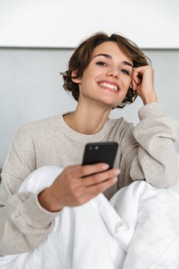 Gülümseyen genç kız yatakta rahatlatıcı