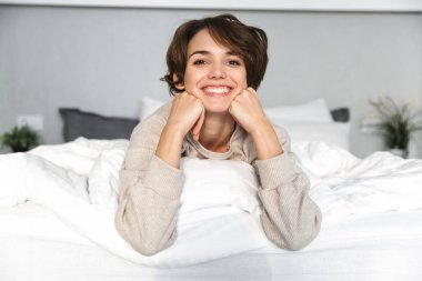 Gülümseyen genç kız yatakta rahatlatıcı