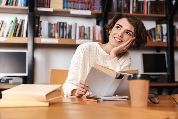 Glückliche junge Studentin studiert in der Bibliothek — Stockfoto