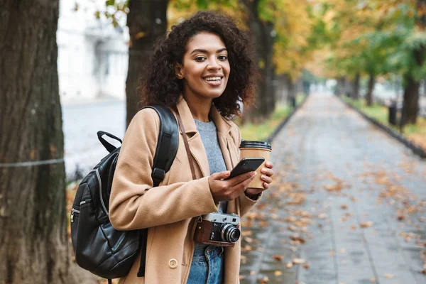 Veselá mladá Afričanka nosí kabát chůzi — Stock fotografie