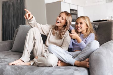 Mutlu kız kardeş evde kanepe kapalı birlikte tv seyretmek.