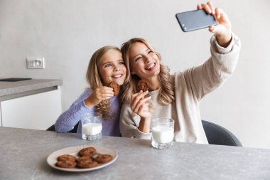 Mutlu kız kardeşler mutfak at kapalı yemek bir selfie telefonla birlikte almak bir kahvaltı yapın.