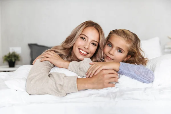 Chicas felices hermanas en la cama en el dormitorio en casa posando sonriente . —  Fotos de Stock