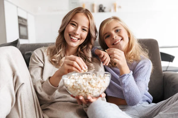 Happy young woman with her little sister indoors at home watch tv.