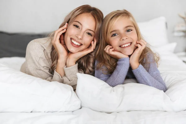 Chicas felices hermanas en la cama en el dormitorio en casa posando sonriente . —  Fotos de Stock