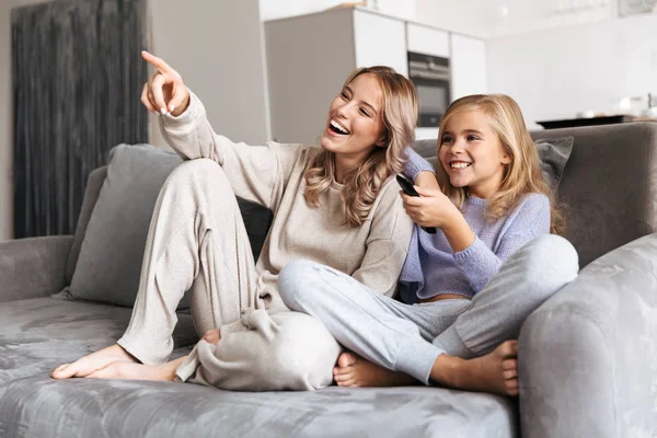 Счастливые сёстры на диване дома смотрят телевизор вместе . — стоковое фото