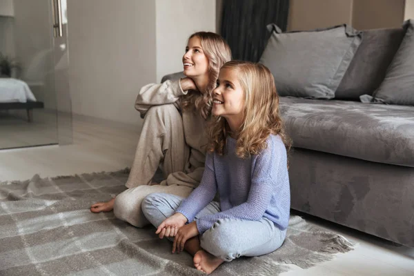 Gelukkig jonge vrouw met haar kleine zusje binnenshuis thuis tv kijken. — Stockfoto