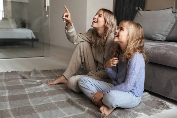 O femeie tânără fericită cu sora ei mai mică în interior la televizor ceas acasă . — Fotografie, imagine de stoc