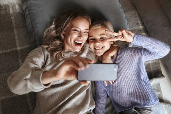 Küçük kız kardeşi olan mutlu kadın kapalı evde cep telefonuyla bir selfie almak. — Stok fotoğraf