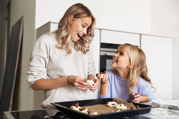 Happy young woman with her little sister indoors at home kitchen cooking sweeties bakery. — Stock Photo, Image