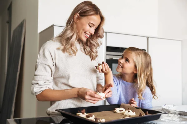 Happy young woman with her little sister indoors at home kitchen cooking sweeties bakery. — Stock Photo, Image