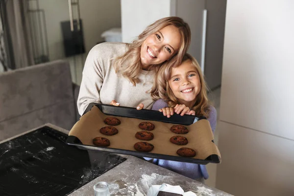 Happy young woman with her little sister indoors at home kitchen cooking sweeties bakery. — Stock Photo, Image