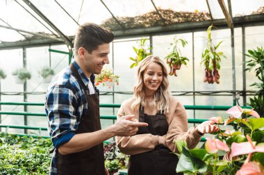 Şaşırtıcı bahçıvanlar çalışmalarında doğa sera bahçe çiçek bitkiler ile poz.