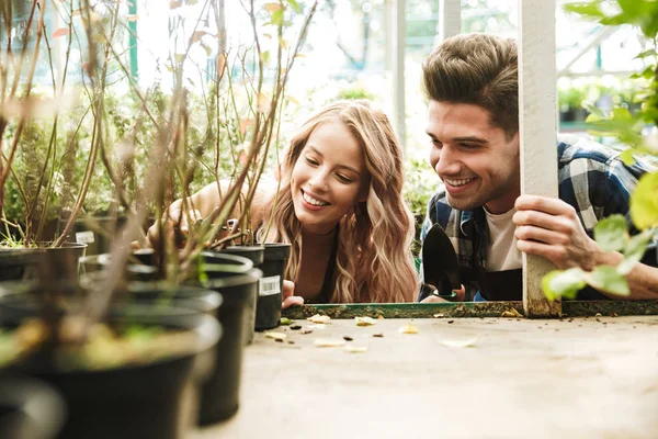 Increíbles jardineros posando en el jardín de invernadero de la naturaleza trabajan con flores plantas . —  Fotos de Stock