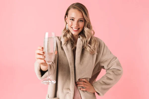 Emocional joven bonita mujer posando aislada sobre fondo de pared rosa sosteniendo vidrio con bebida alcohólica . — Foto de Stock