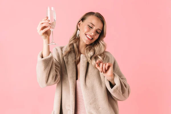 Emotionale junge hübsche Frau posiert isoliert über rosa Wand Hintergrund hält Glas mit Alkohol trinken. — Stockfoto